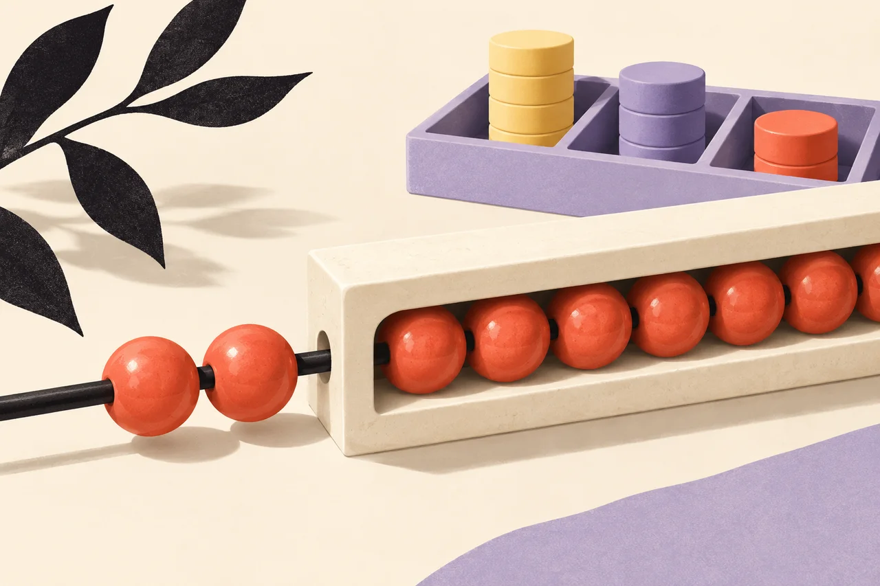 Coral beads stay threaded through an ivory channel beside a tray of stacked quantity counters.