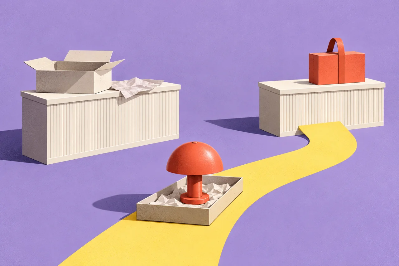 An unpacked coral lamp sits on a yellow route between an unfinished packing counter and a counter holding a closed parcel.